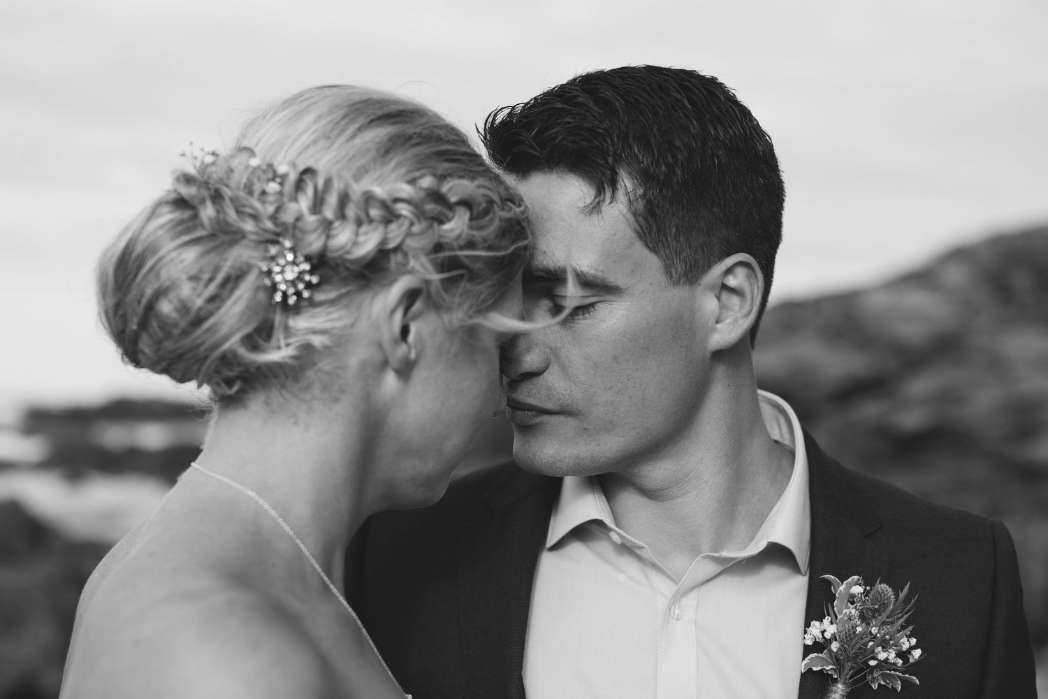 An intimate black and white portrait of newlyweds sharing a romantic moment.