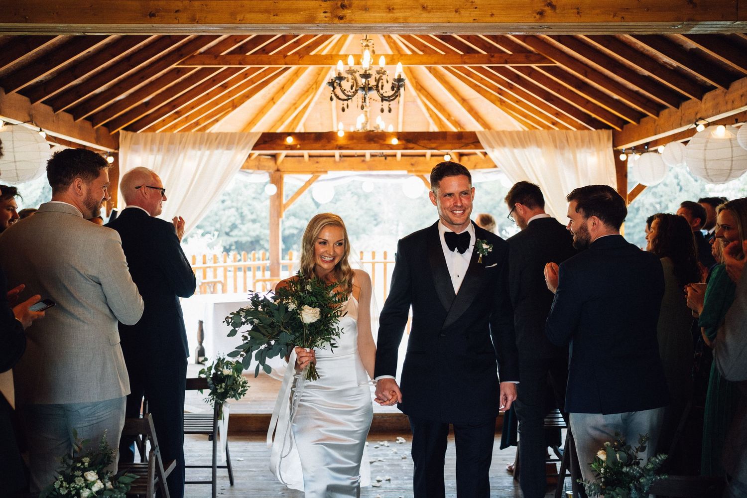 Elegant wedding reception venue with exposed wooden beams and chandelier lighting.