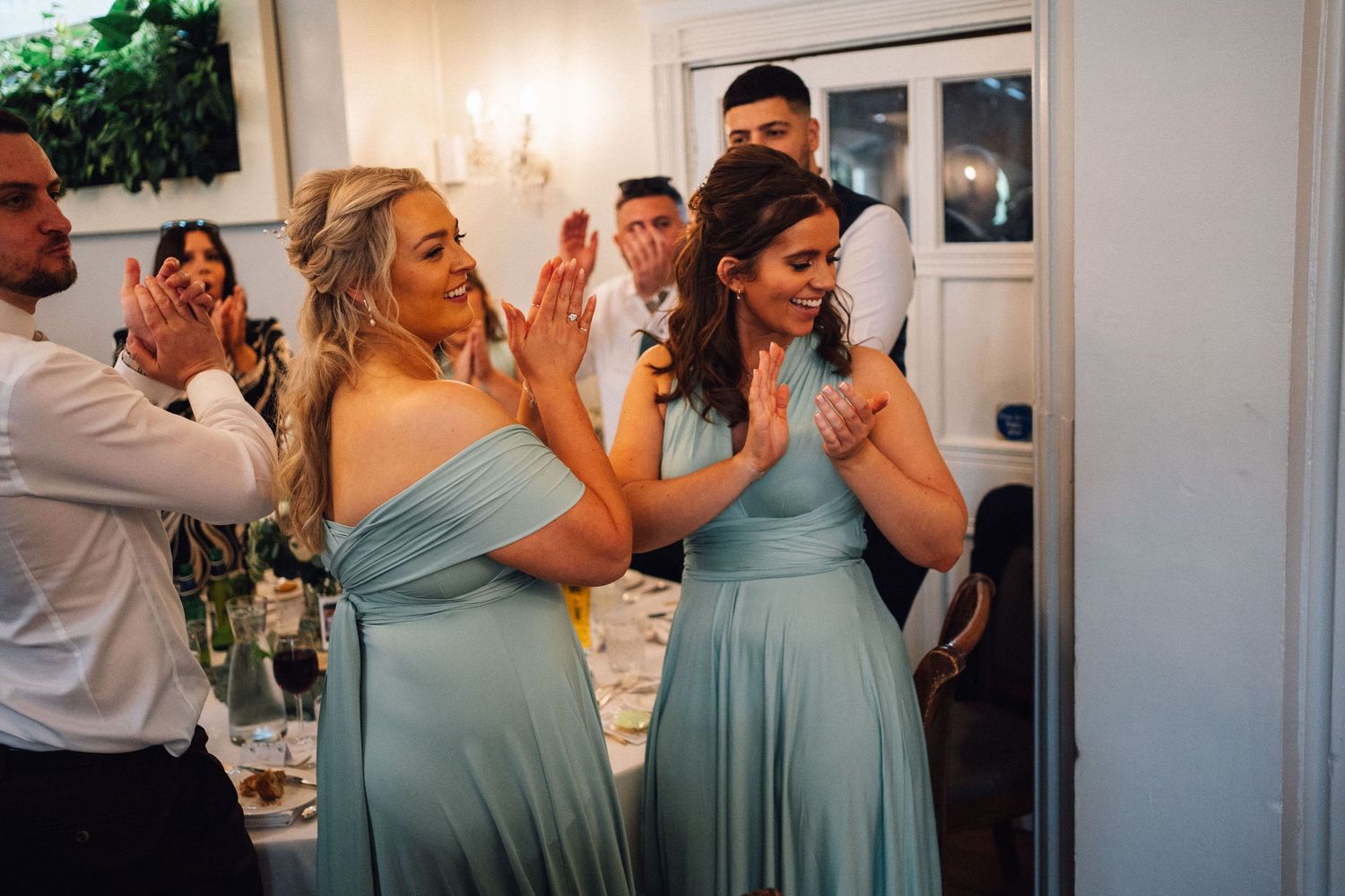 Bridesmaids in light blue dresses react emotionally during wedding reception celebrations.