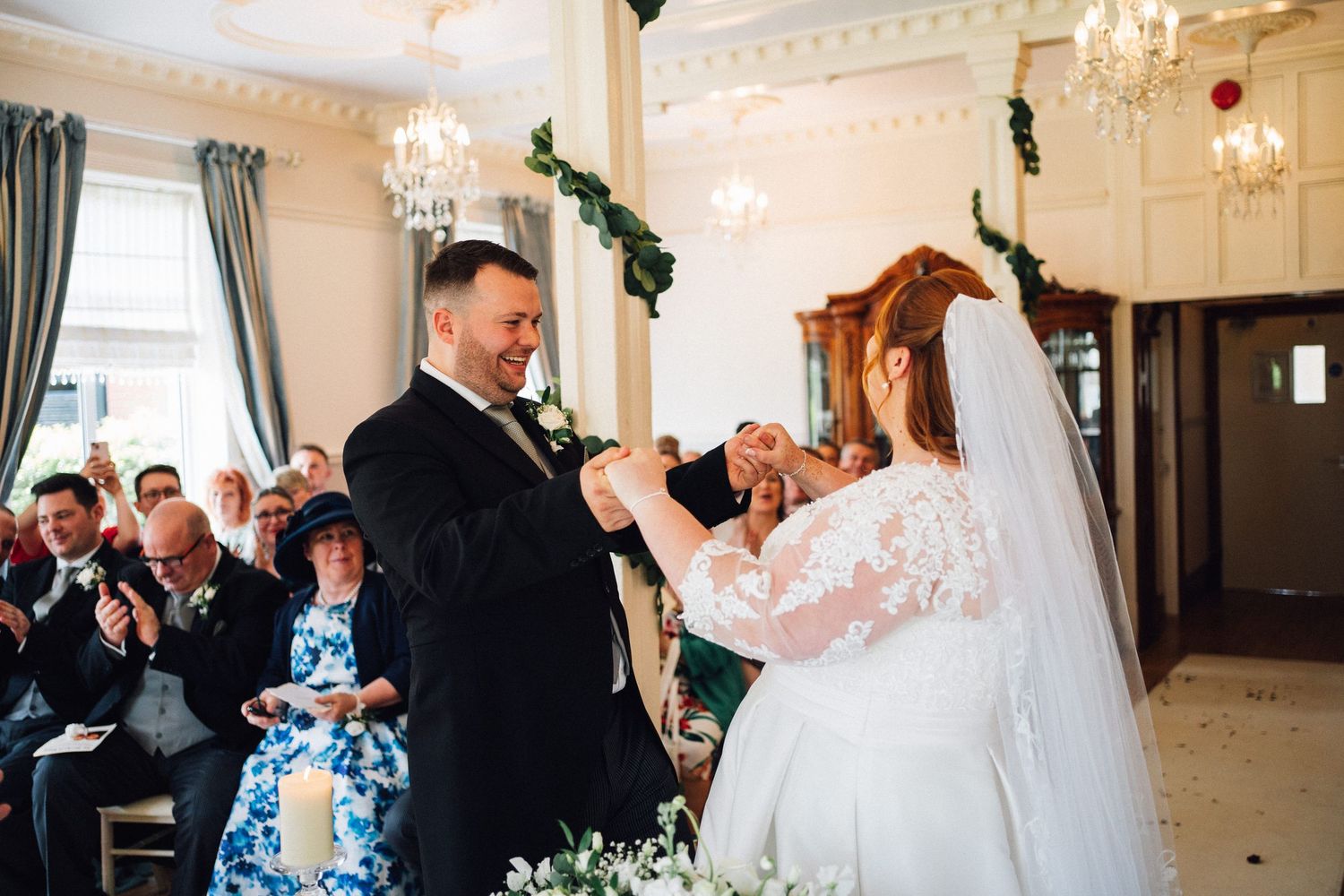 Wedding guests celebrating with confetti and laughter during an elegant indoor ceremony.
