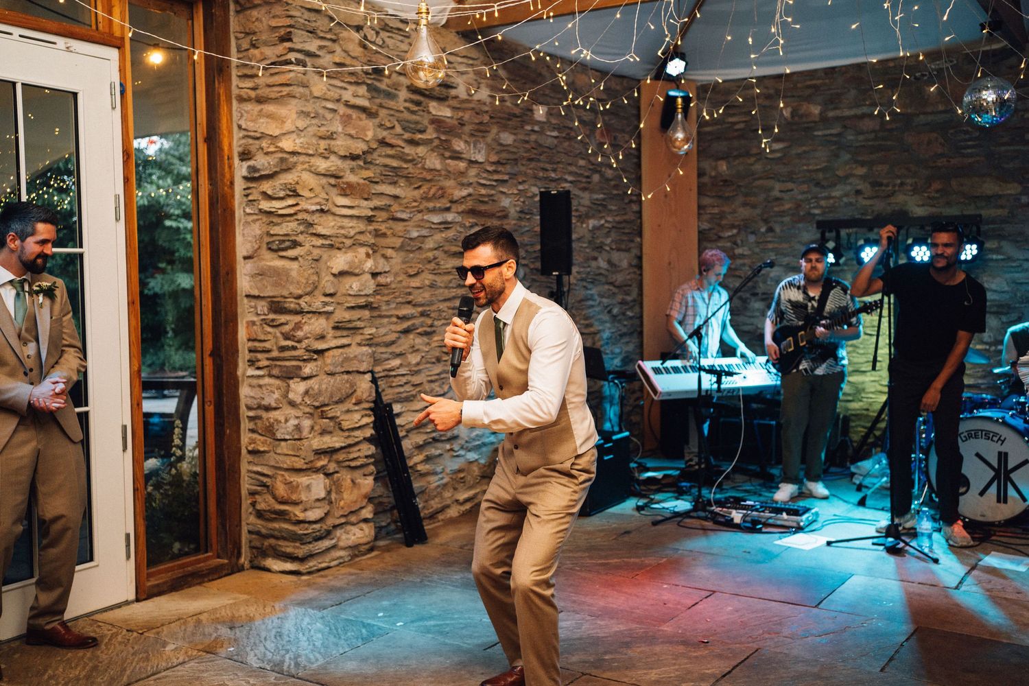 Wedding reception dance floor with colored lighting and stone wall backdrop.
