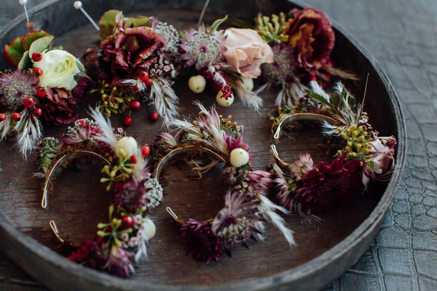 Dried floral arrangements with burgundy and pink blooms displayed on rustic wooden surfaces.