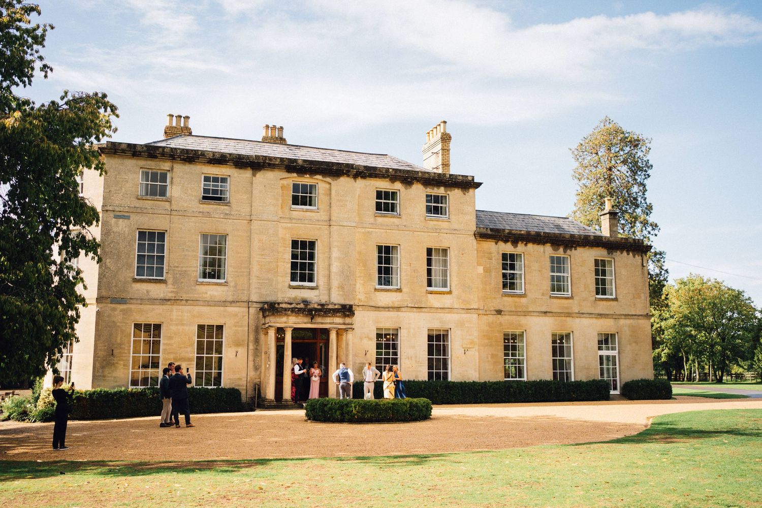 Large Georgian-style mansion with symmetrical windows and grand entrance on a sunny day.