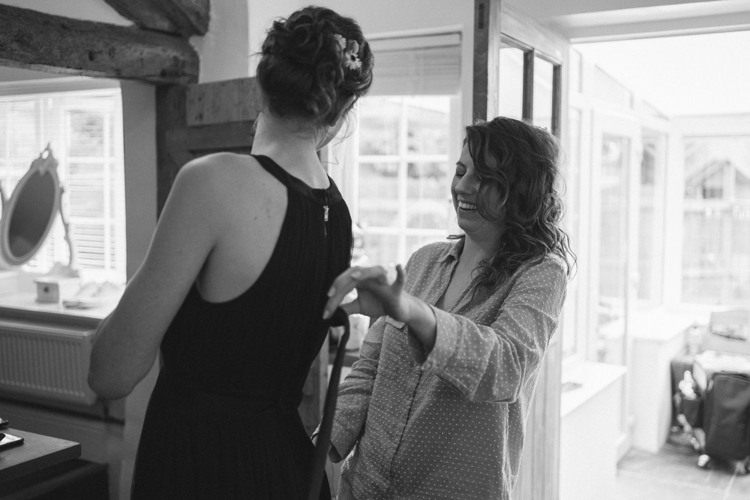 Wedding preparations captured in black and white photography near bright windows.