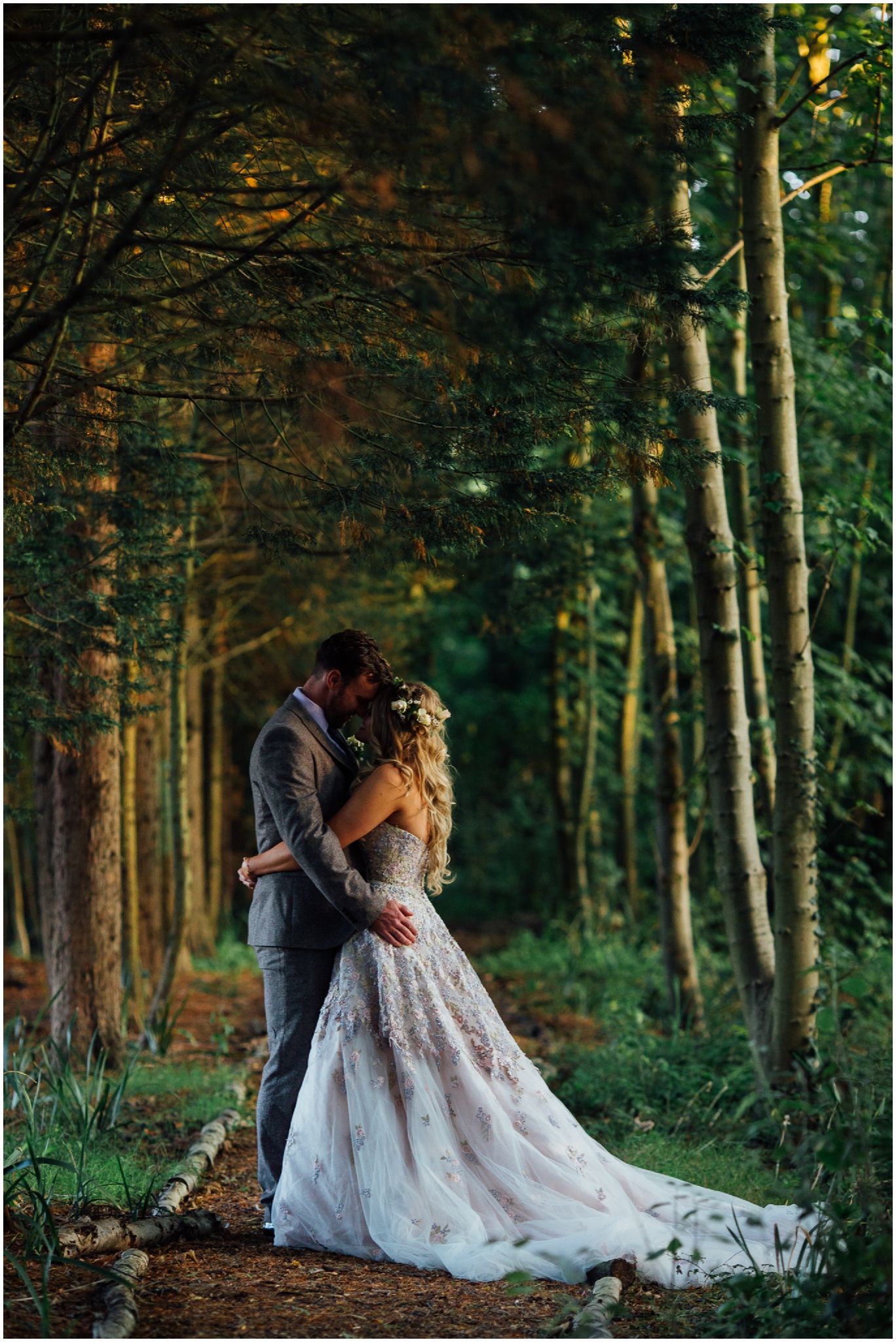 Romantic forest wedding portraits with dramatic lighting through trees.
