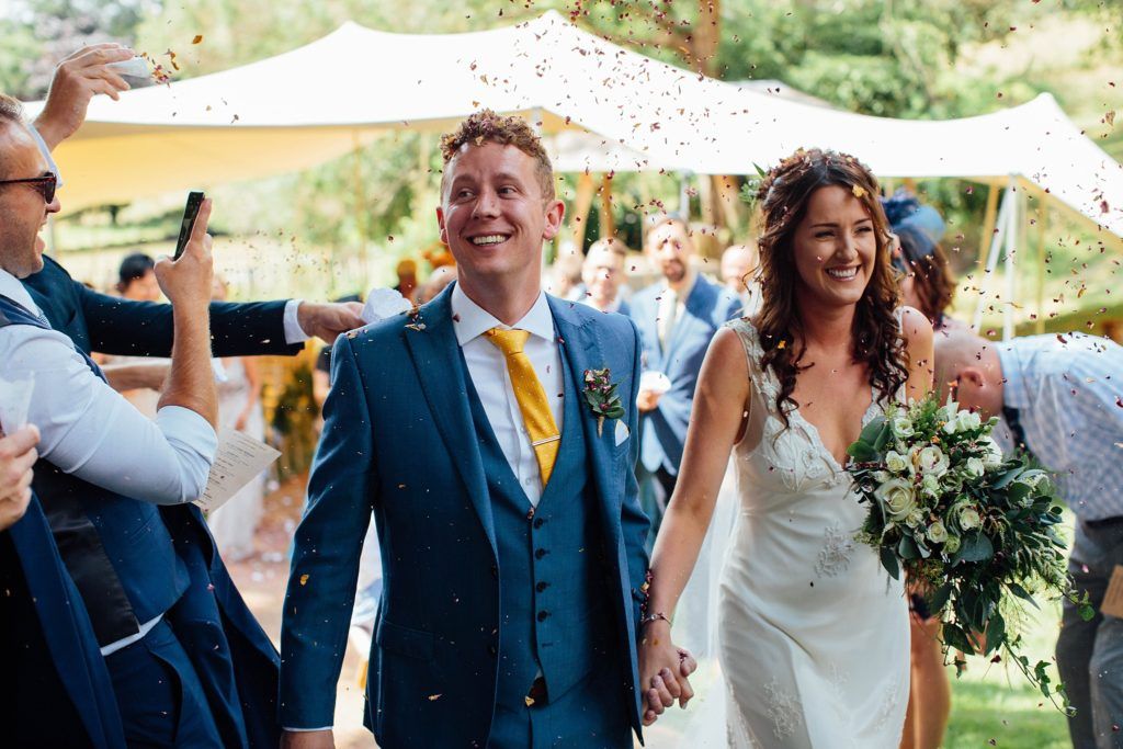 Guests celebrate during a lively outdoor wedding reception under a tent.