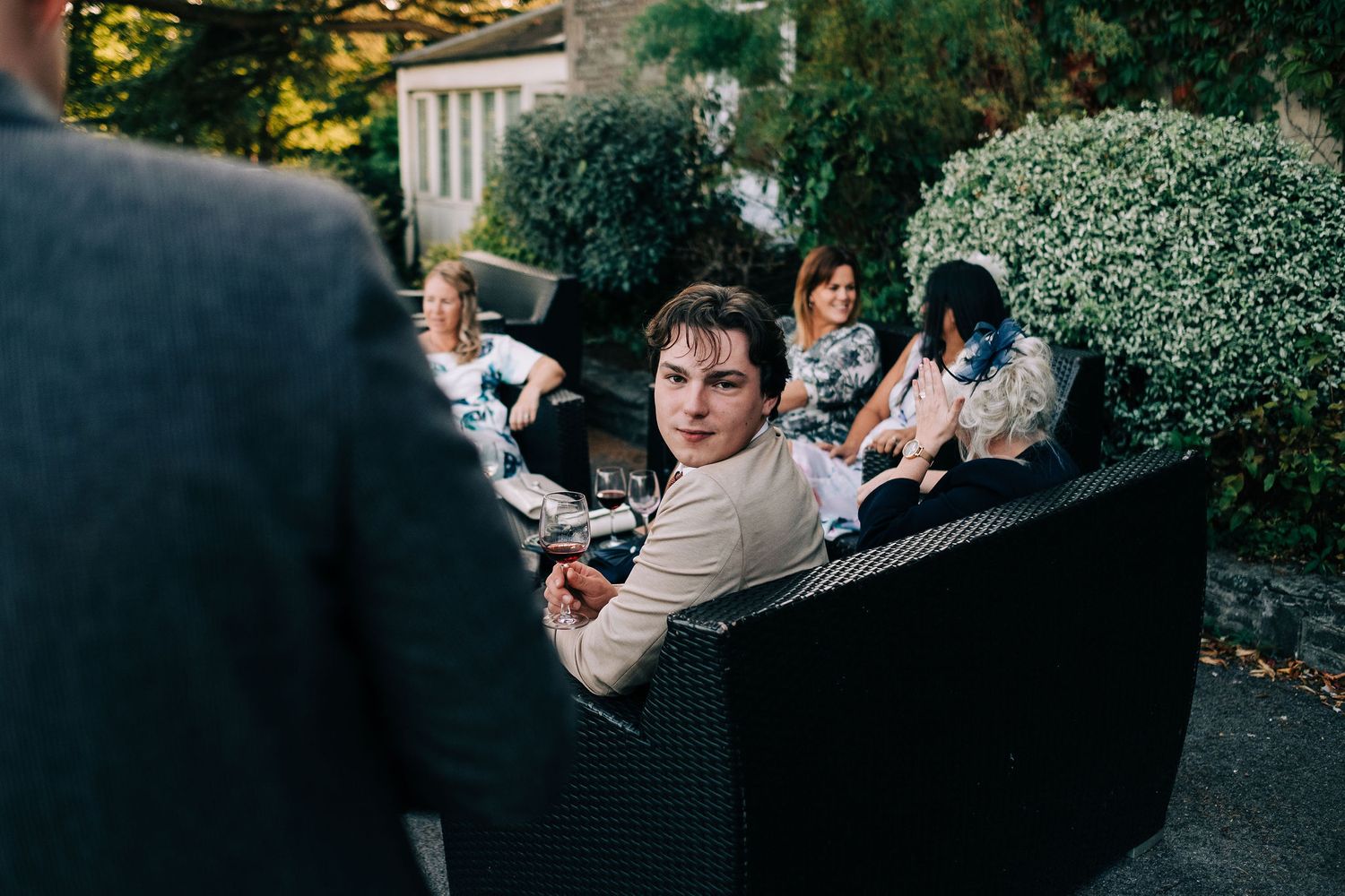 Natural candid interactions between wedding guests in outdoor garden setting.