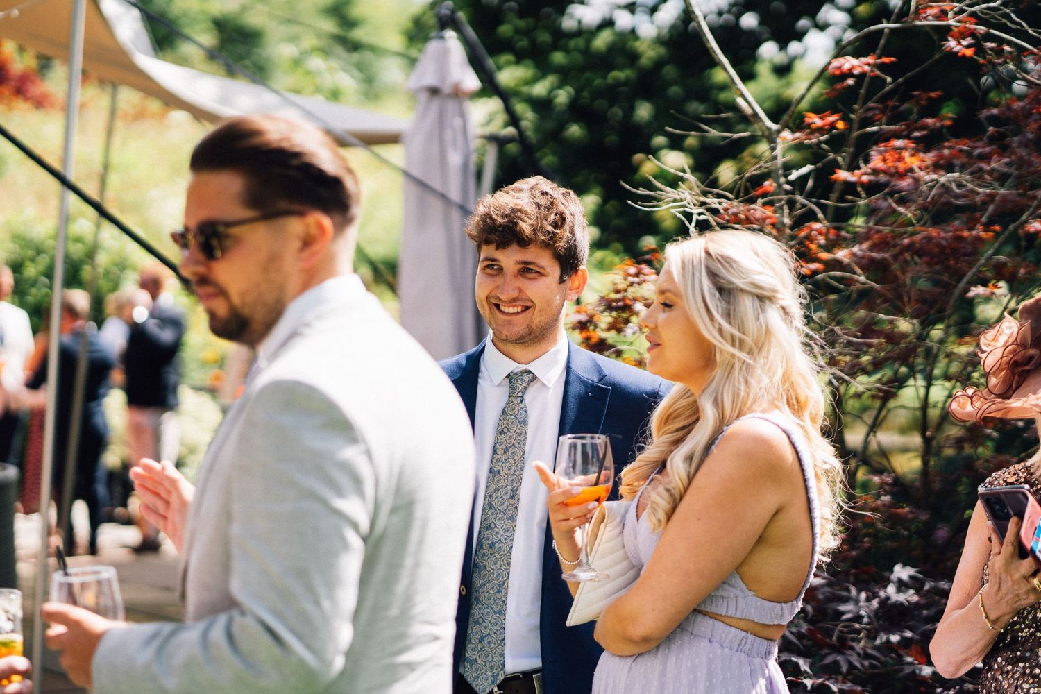 Festive outdoor gathering with guests mingling in a landscaped garden setting.