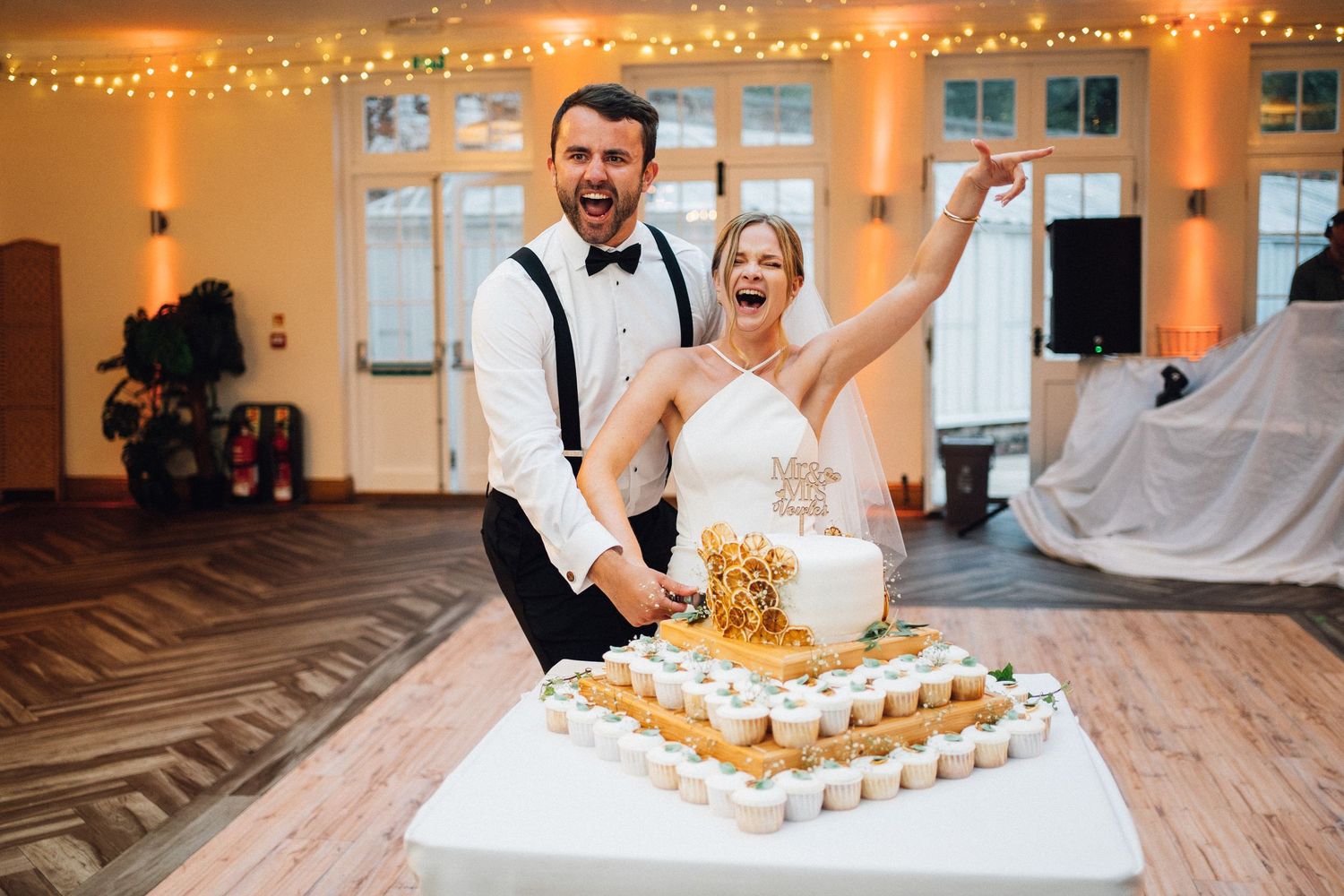 A couple celebrating at their wedding reception with a tiered display of cupcakes.
