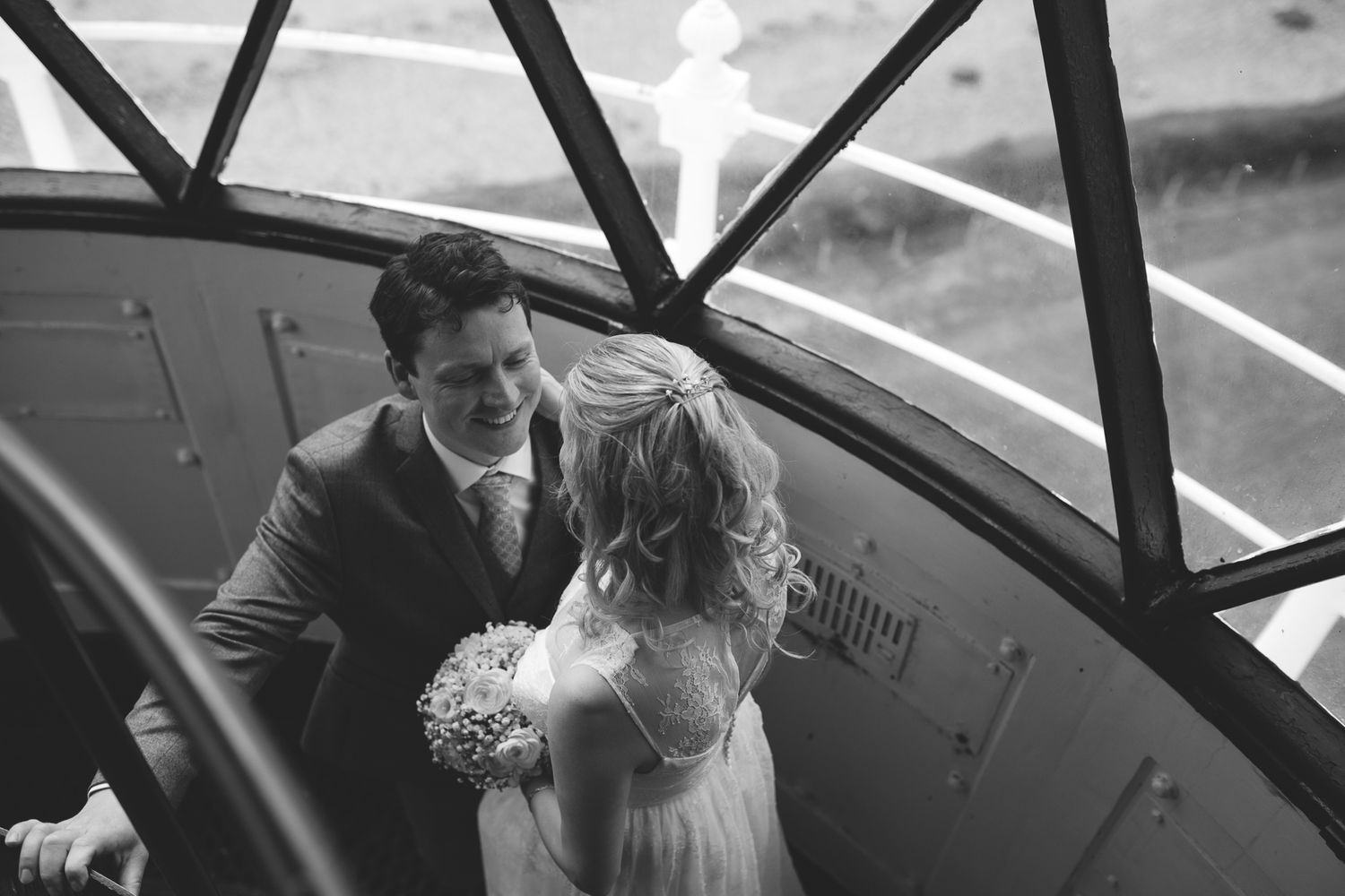 Black and white photo of couple sharing tender moment in airplane cockpit.