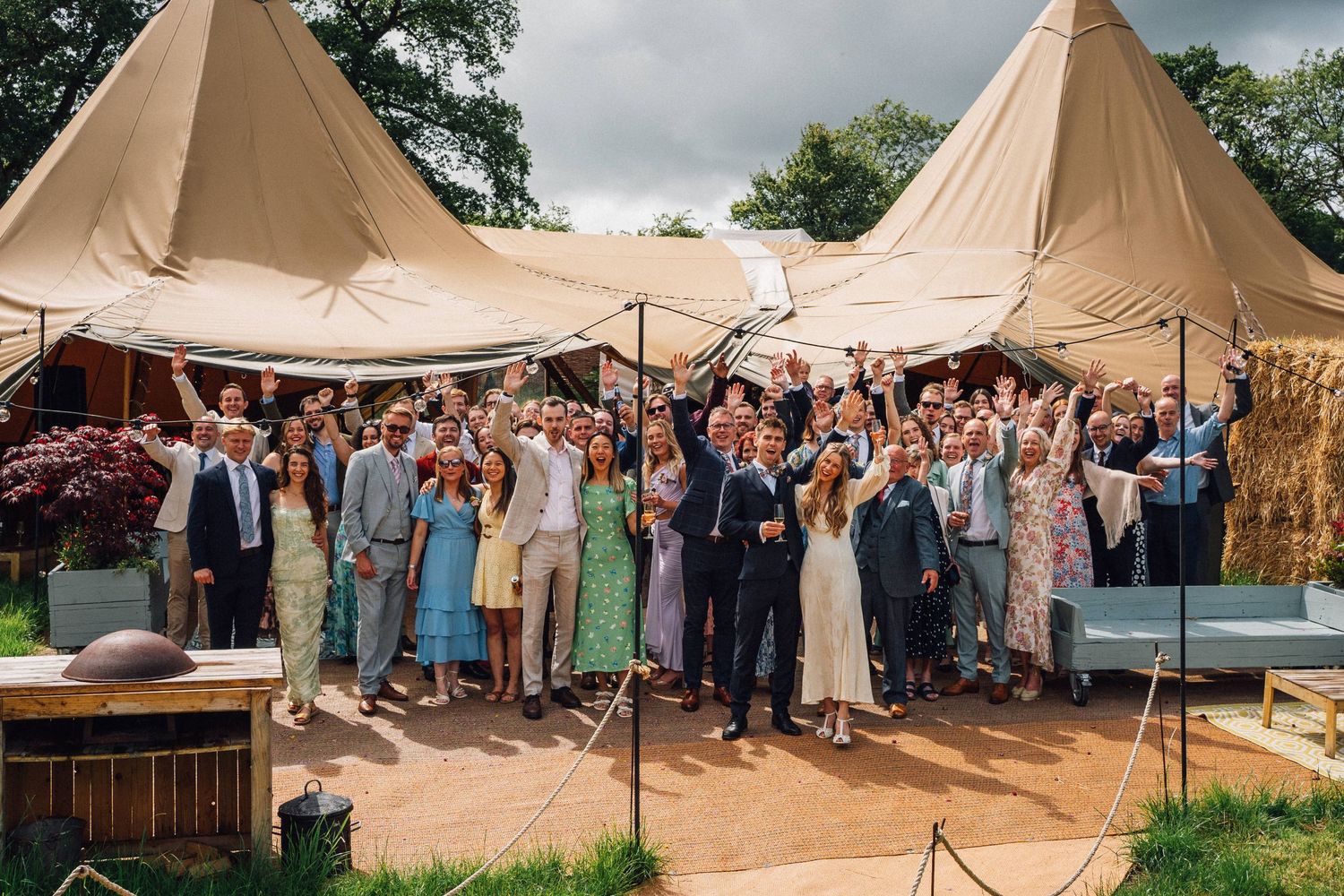 Large tipi-style wedding tent filled with celebrating guests at an outdoor reception.