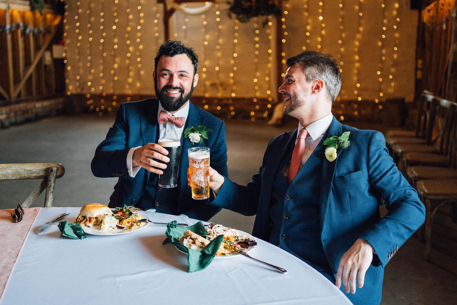 Wedding reception venue decorated with warm string lights as guests gather at dining tables.