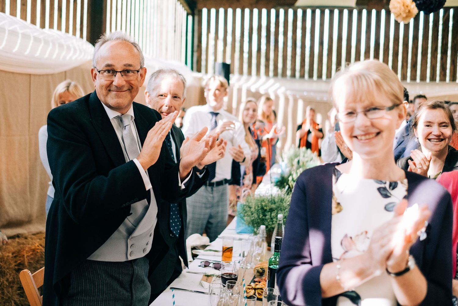 Wedding reception guests smile and applaud during speeches.