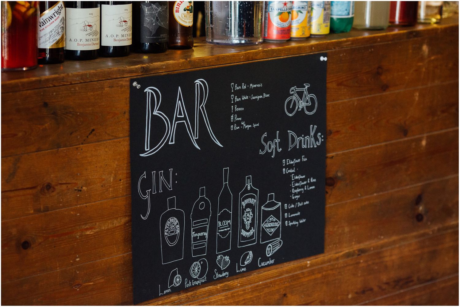 Rustic wooden bar wall with chalkboard menus displaying drink options and prices.