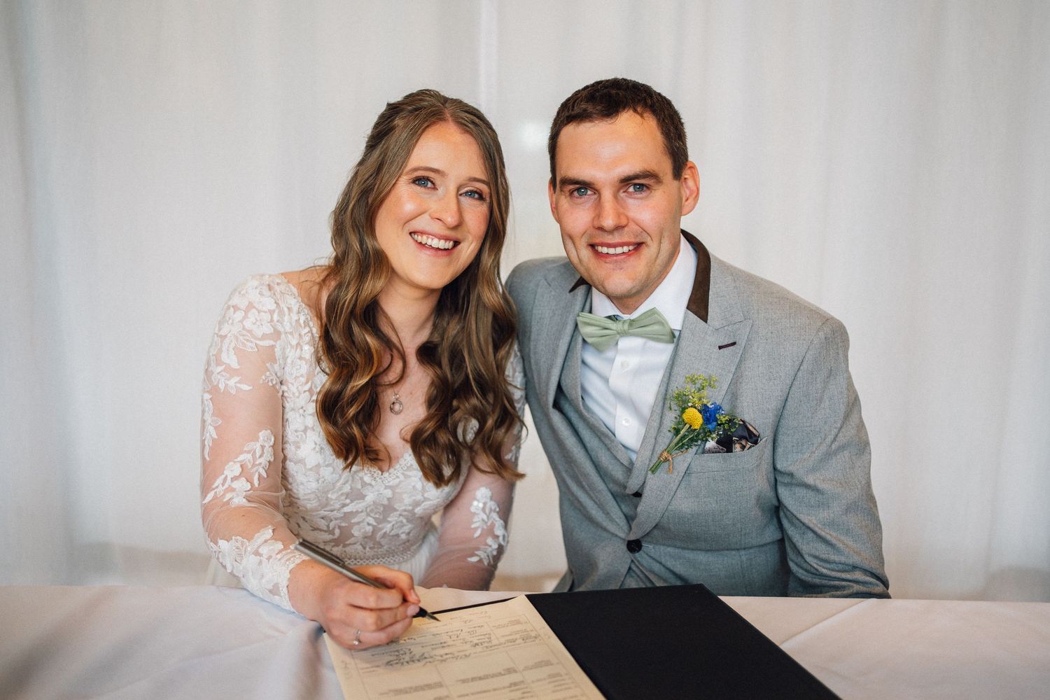 Couple sharing joyful moments while signing documents together at their wedding ceremony.
