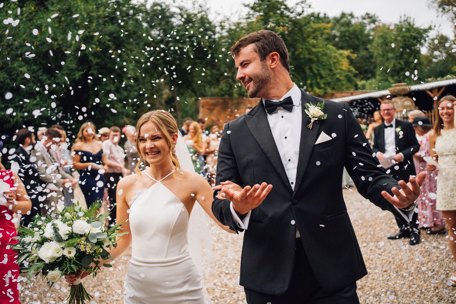 Wedding guests celebrate with confetti throws during an outdoor ceremony celebration.