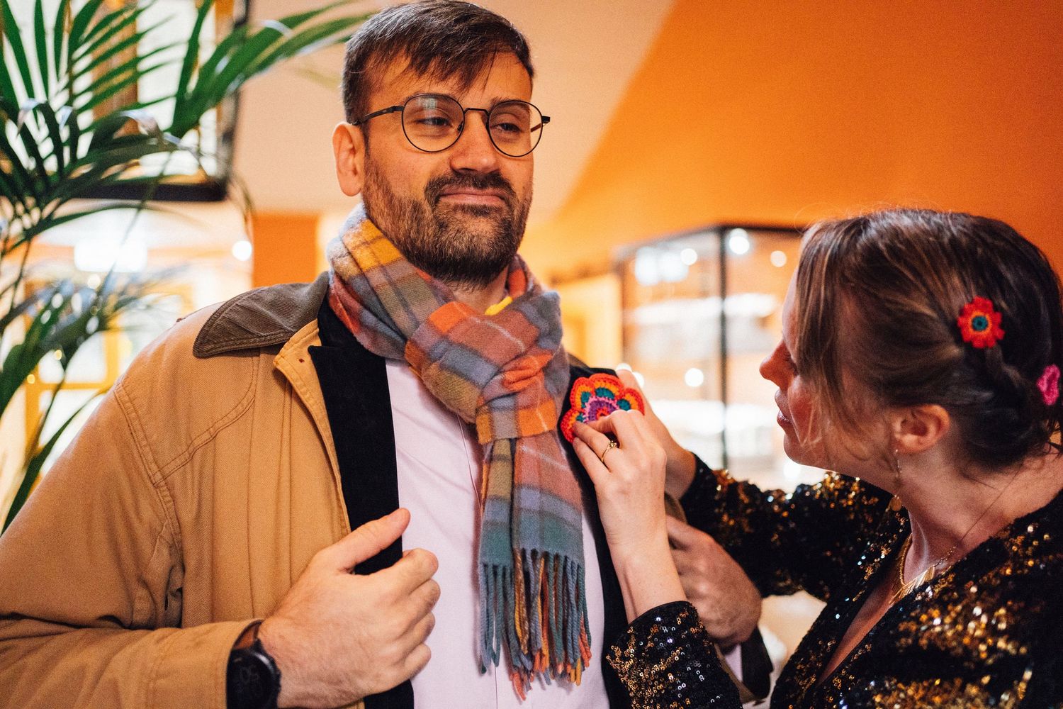 A sequence of photos showing warm interactions between people in a cozy indoor setting with orange lighting.