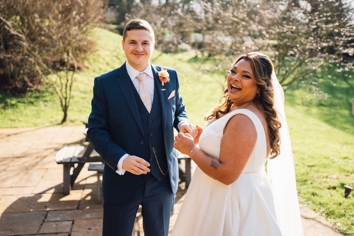 A joyful couple shares a candid moment outdoors on their wedding day.