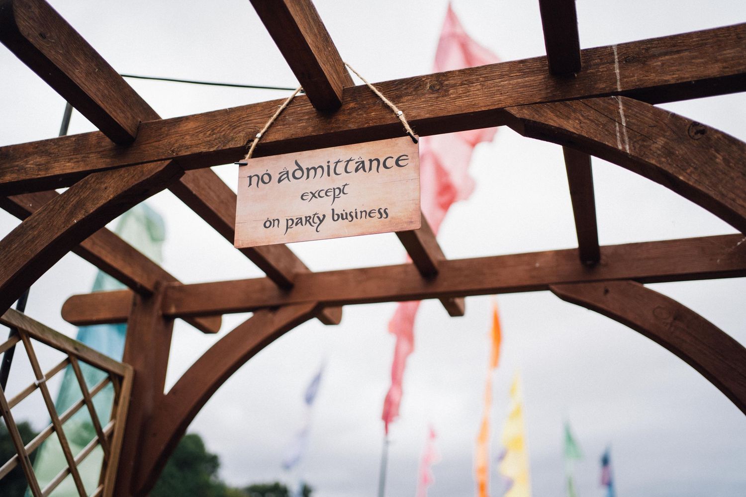 Wooden beam with 'No wholerance' sign hanging among colorful flags.