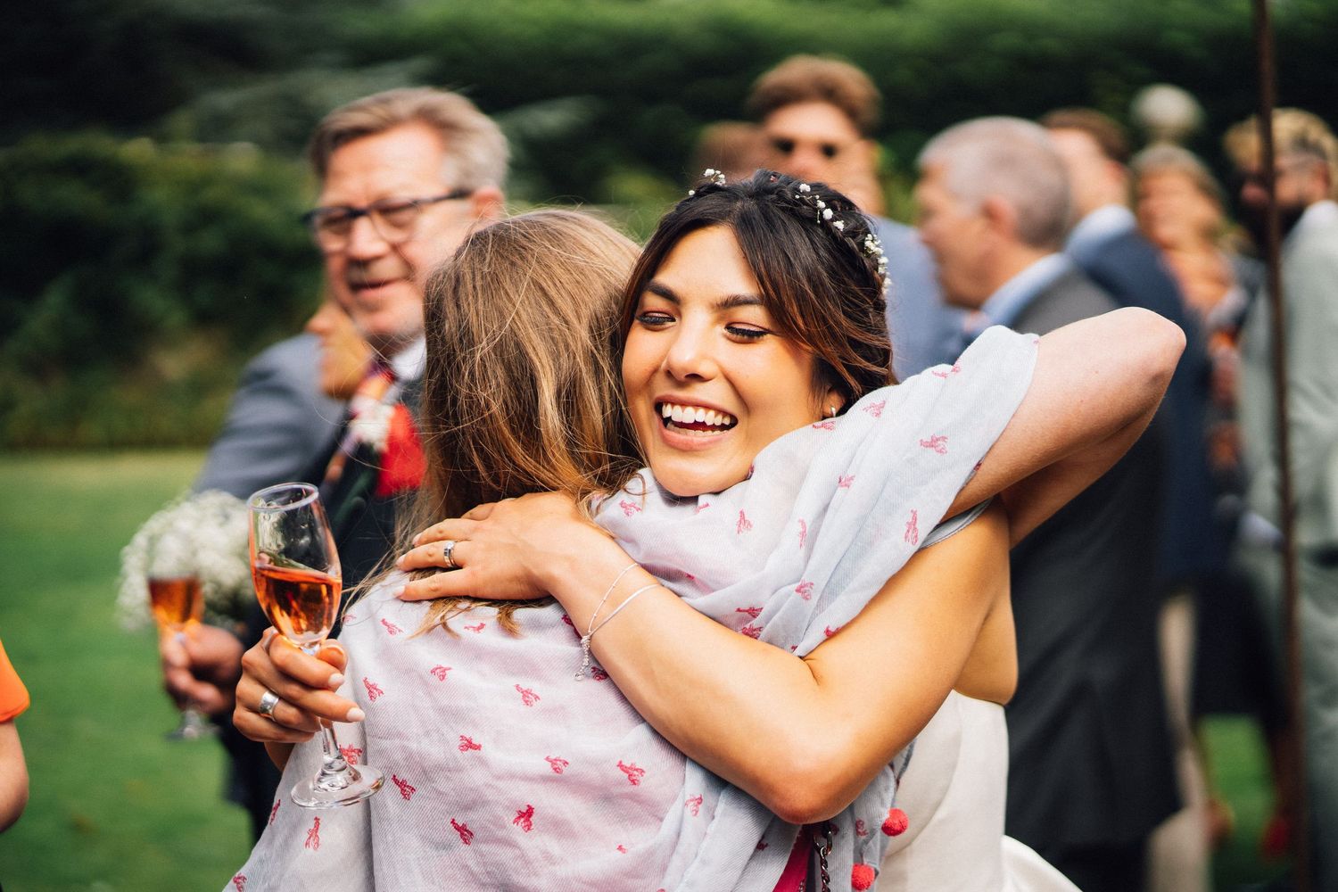 Wedding guests celebrate and embrace during an outdoor reception.