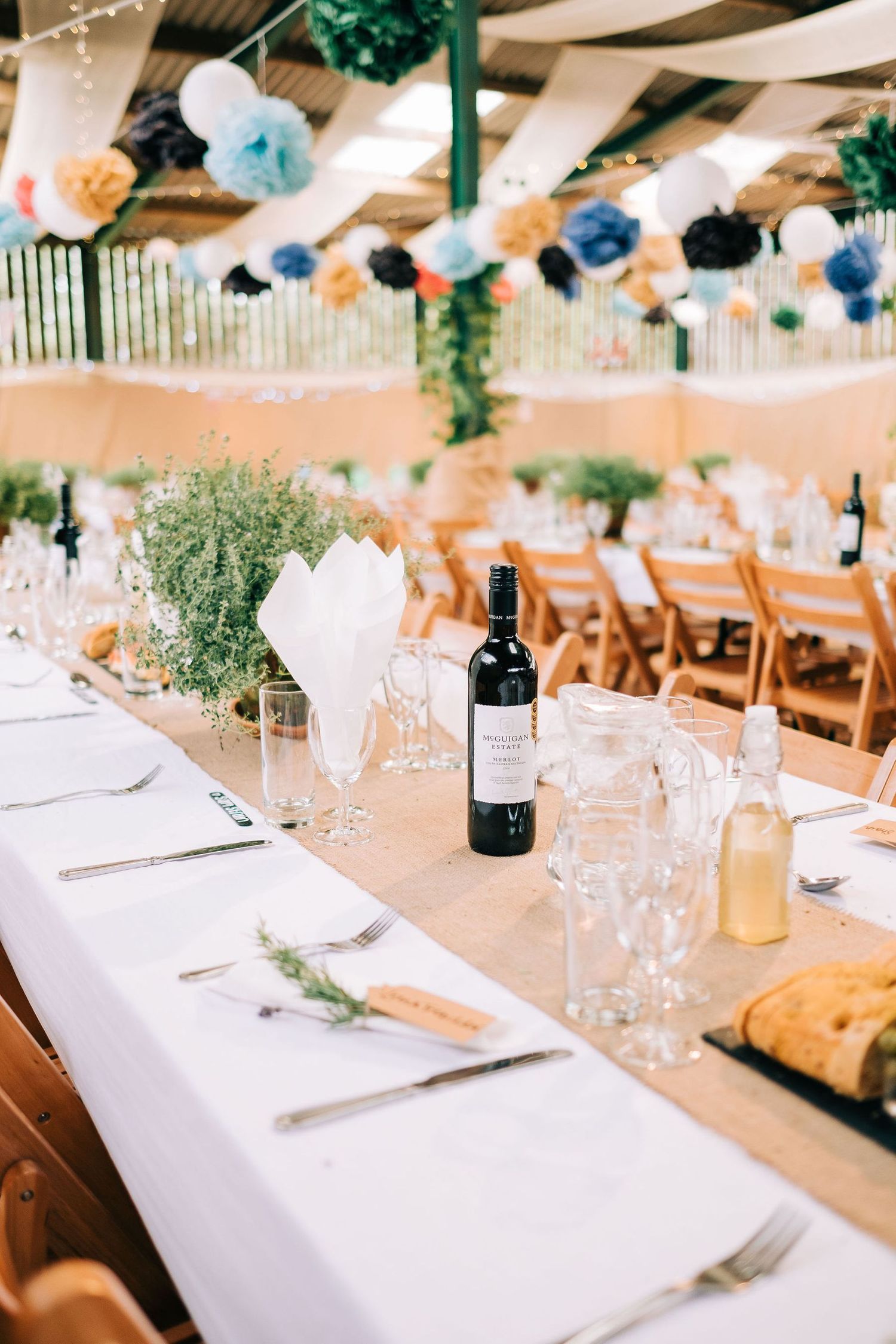 Elegant wedding reception tables set with white linens and wine glasses under string lights.