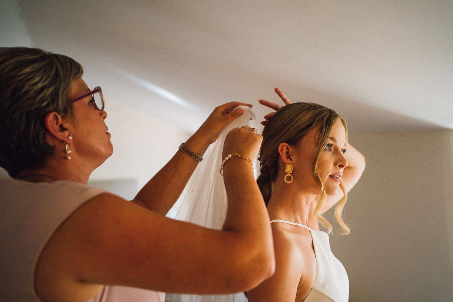 A tender moment captured during wedding preparations in a sunlit room.