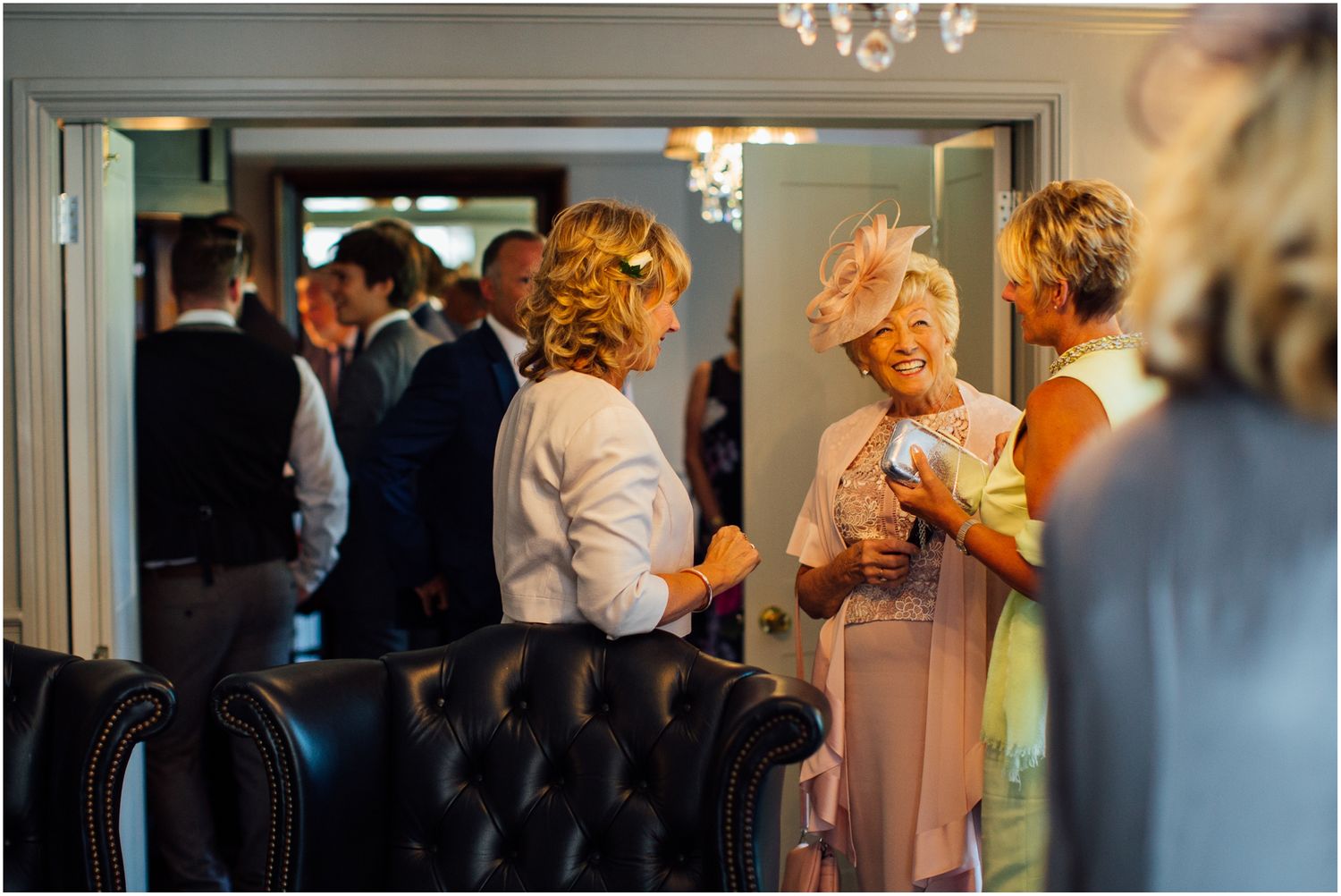 Guests mingle and socialize during an elegant indoor wedding reception with chandeliers.