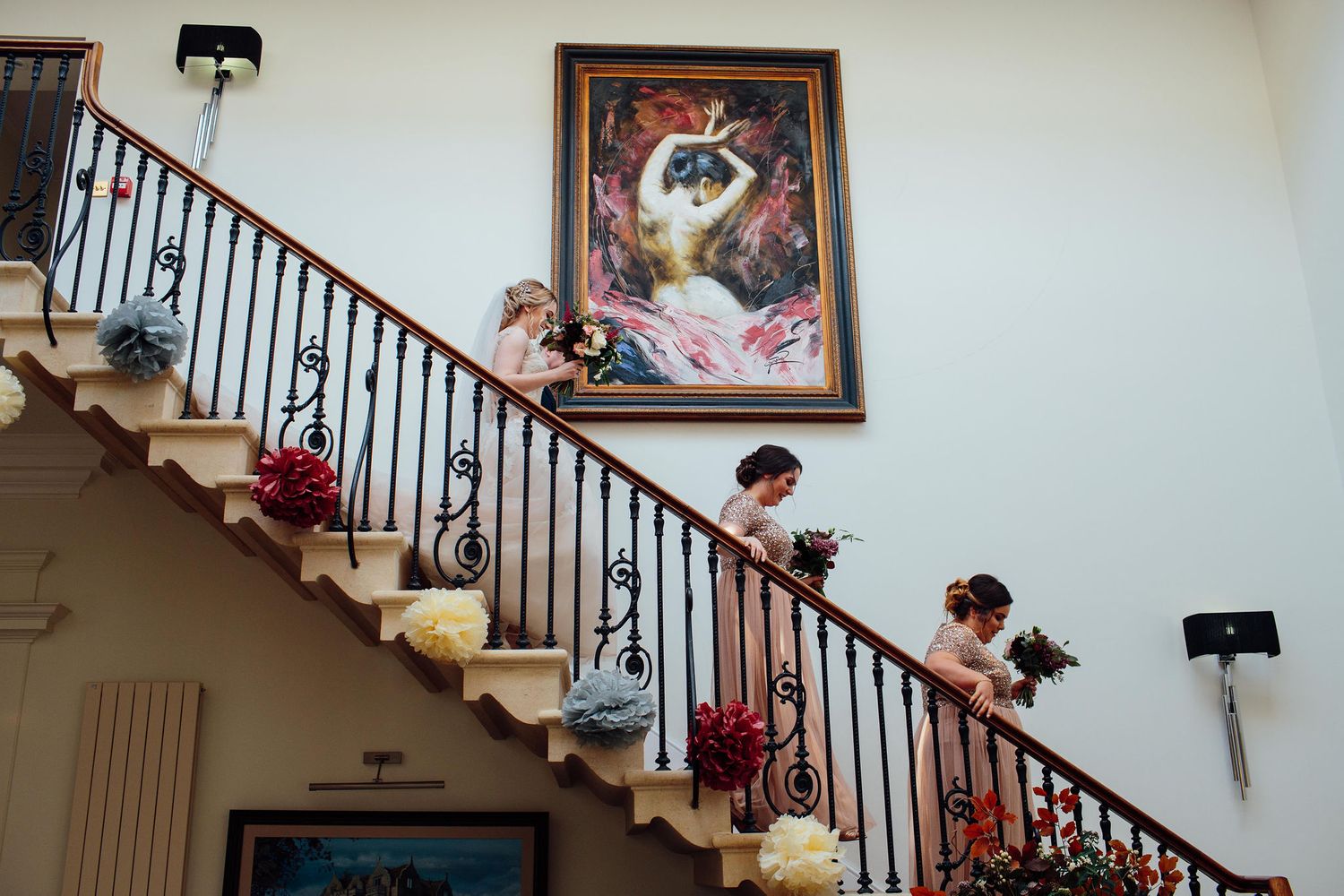 Grand staircase with ornate railings and decorative artwork displayed on white walls.