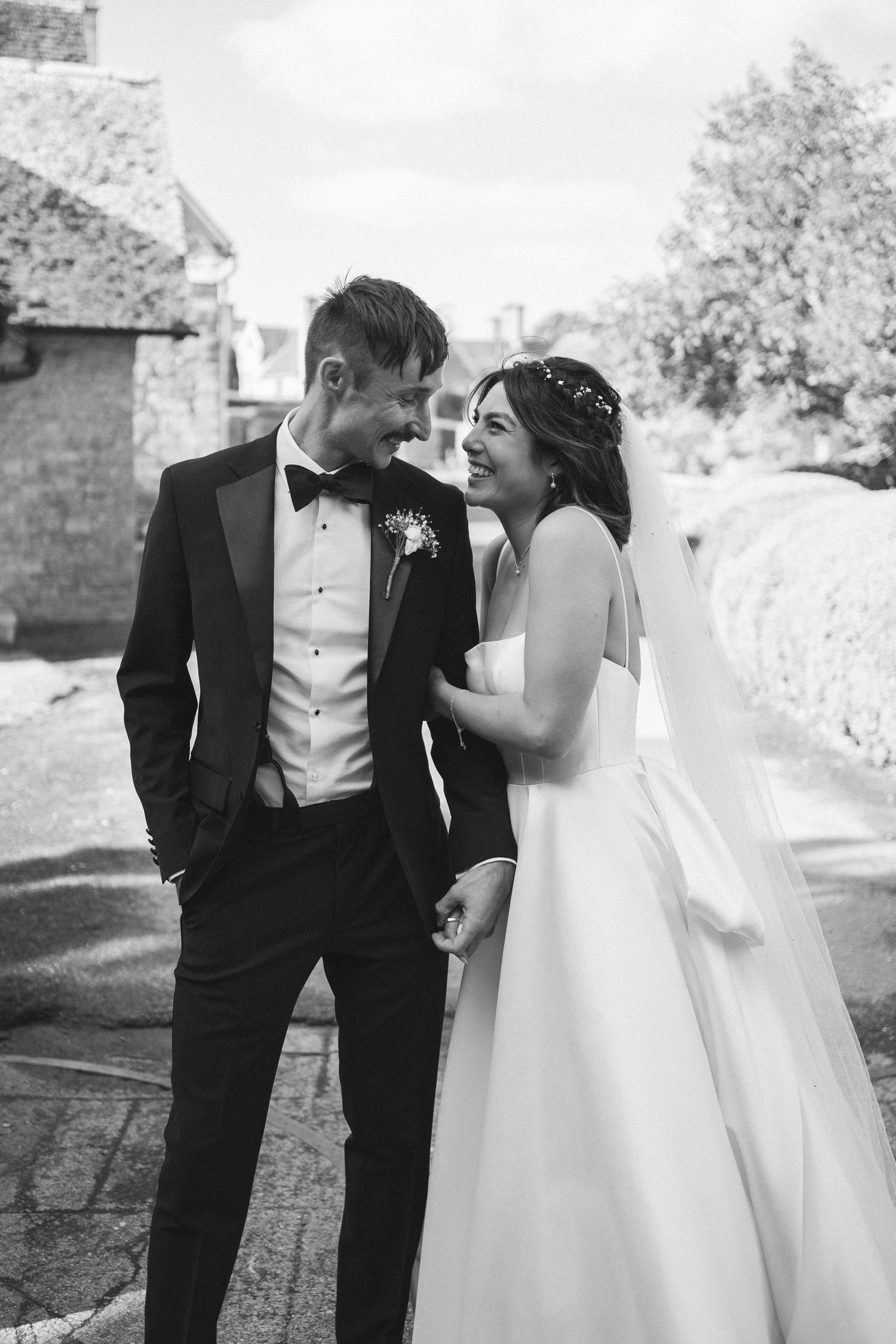 A romantic black and white wedding photo of a couple sharing an intimate moment outdoors.