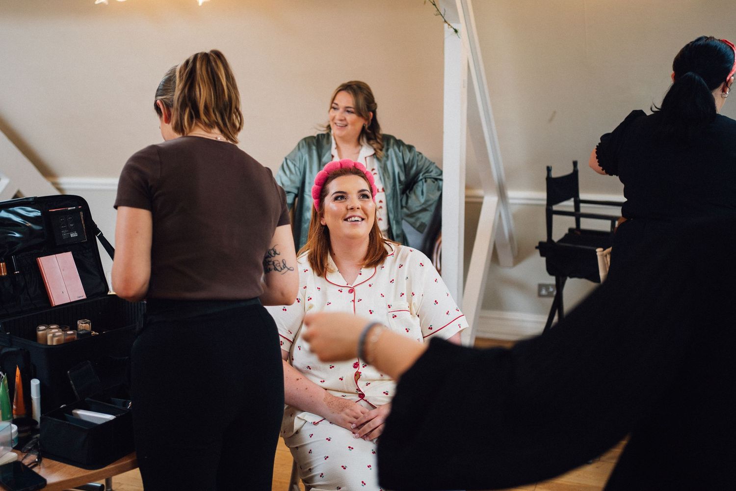 Behind the scenes photo of a makeup and styling session in a bright indoor setting with professional equipment.