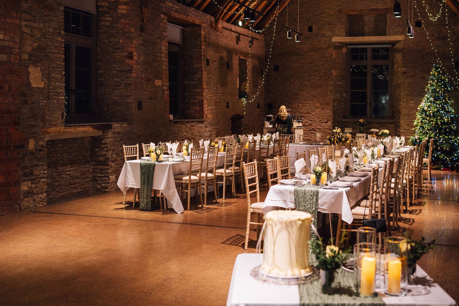 Rustic barn wedding reception venue with elegant table settings and warm lighting illuminating exposed brick walls.