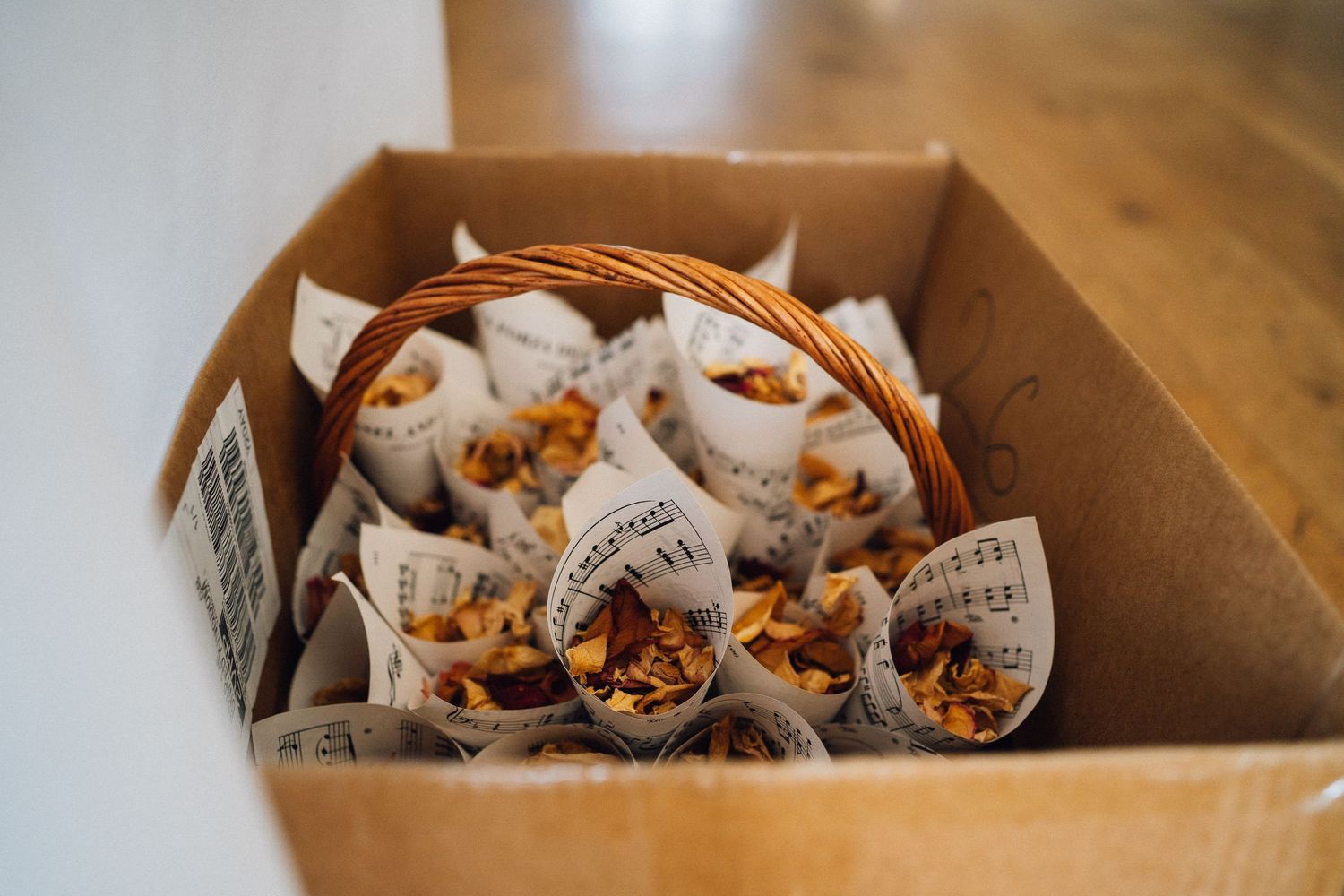 Rustic wooden table with paper cones filled with nuts and snacks arranged in a box for serving.