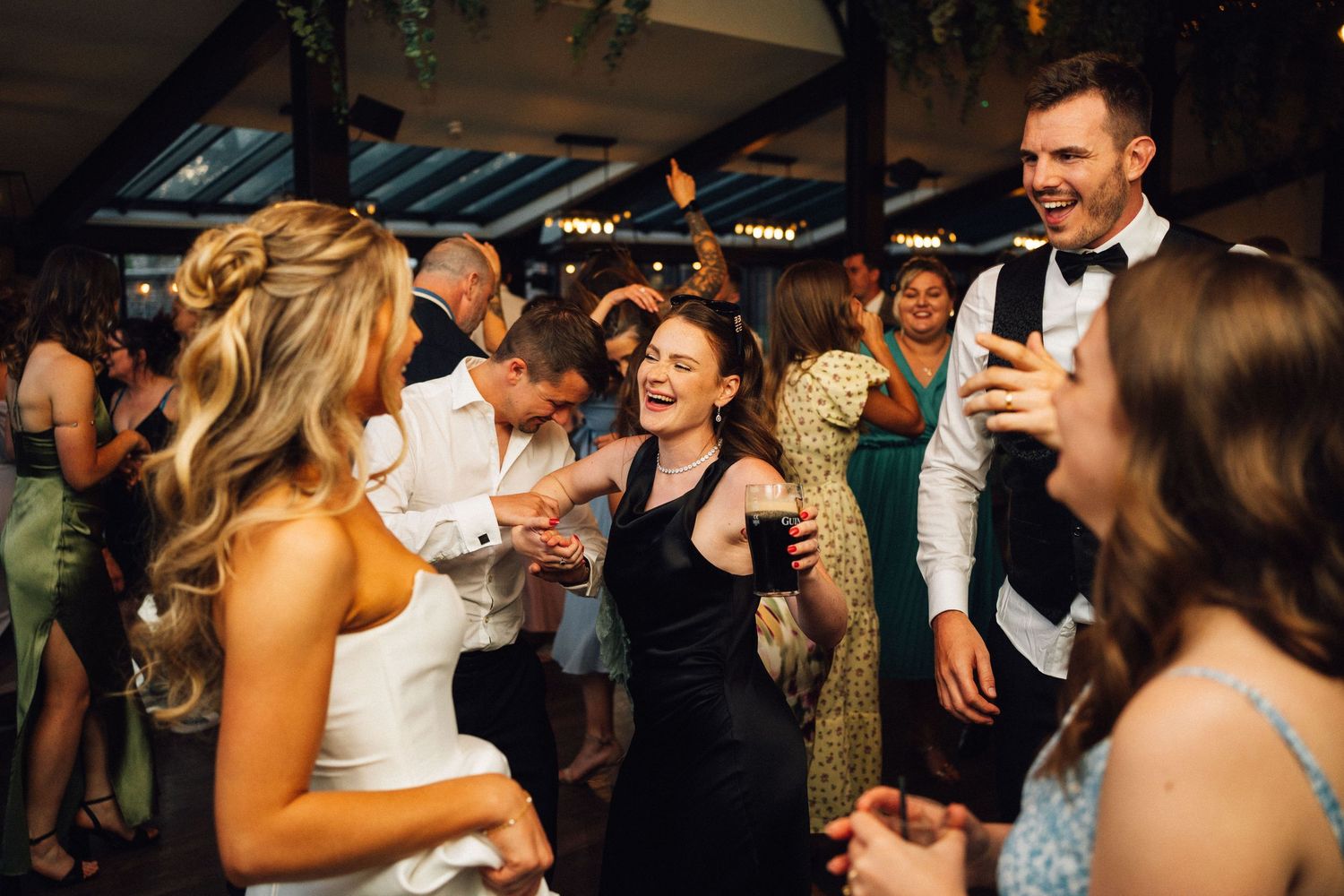 People dancing and celebrating at a lively wedding reception party with warm lighting and joyful atmosphere.
