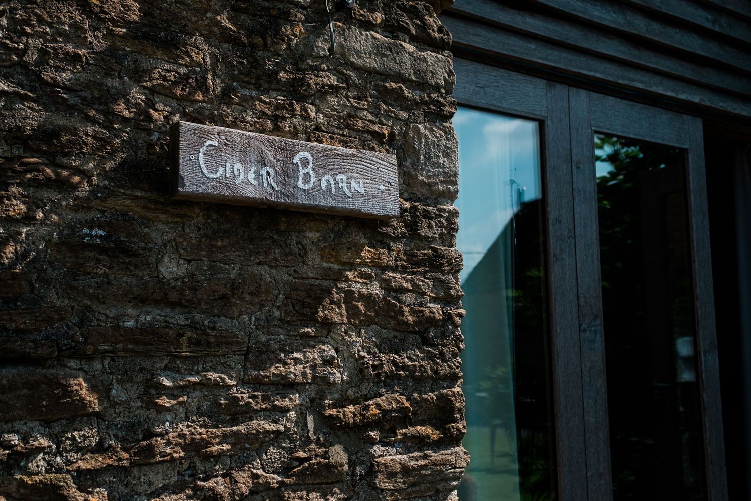 Close-up of rustic stone wall texture with dark wooden shutters at a historic venue.