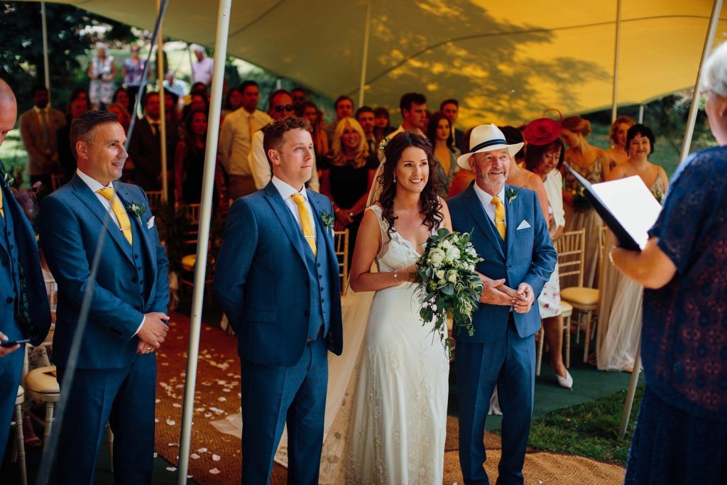 Wedding guests enjoy live entertainment under a white tent at an outdoor reception.