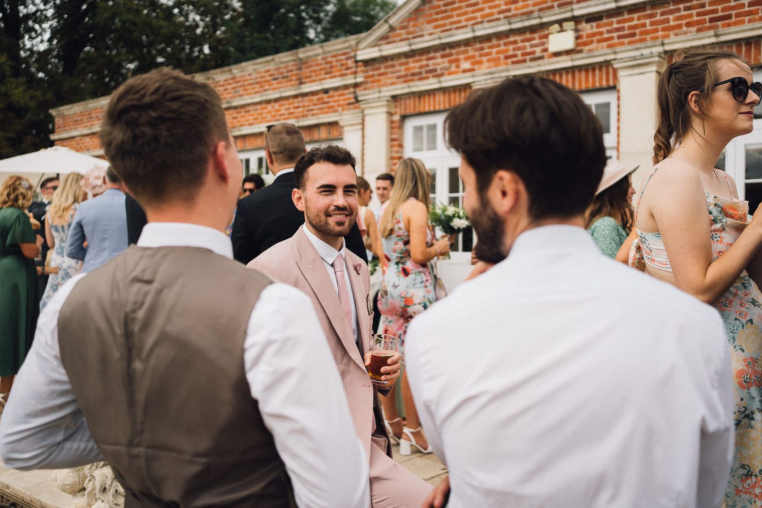 Guests enjoying a summer wedding reception outside a traditional brick venue.