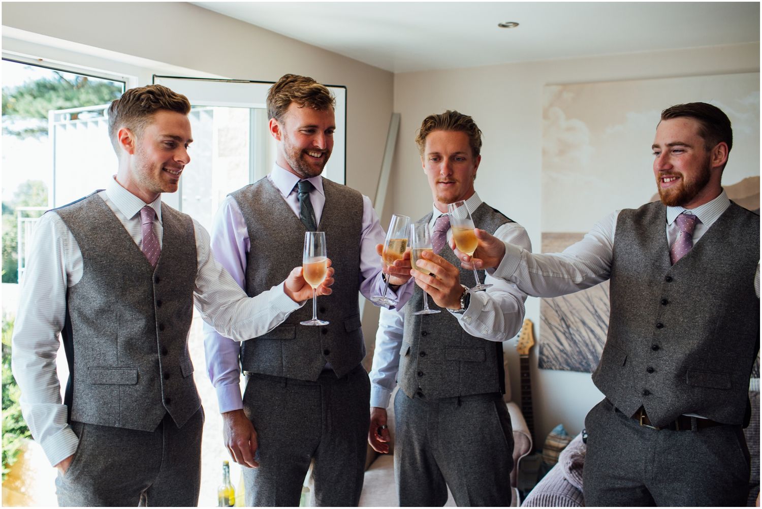 Four people in matching grey vests toast with drinks during a celebration.