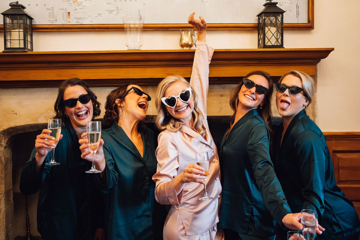 Wedding guests wearing sunglasses pose playfully indoors during celebration.
