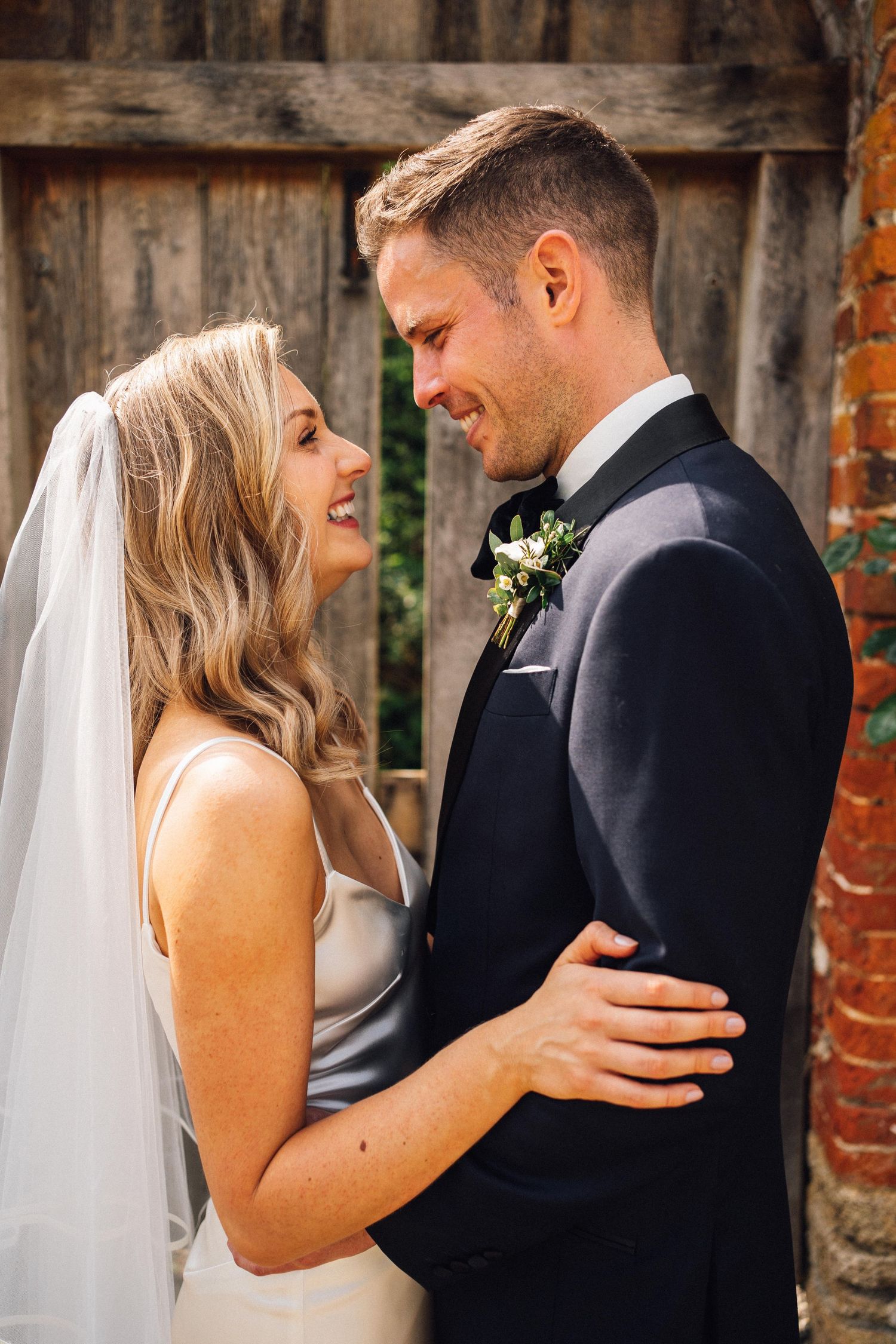 Series of intimate wedding portraits showing couple embracing against rustic brick wall backdrop.