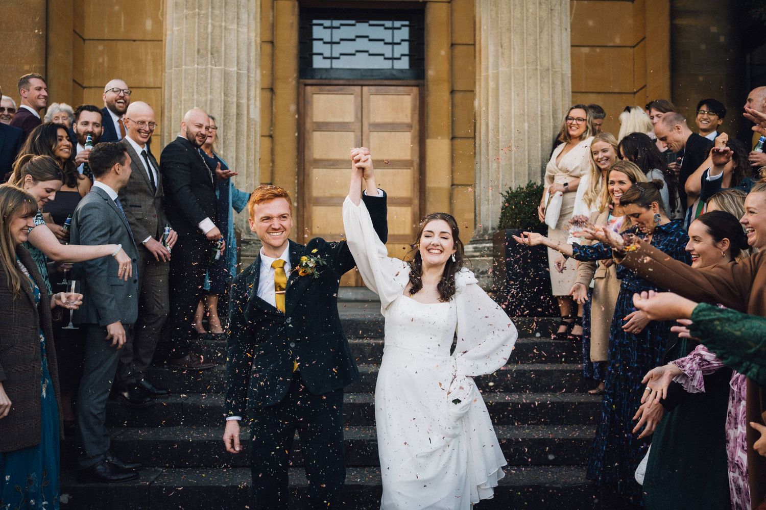 Guests gathered outside a historic stone building for a wedding celebration.