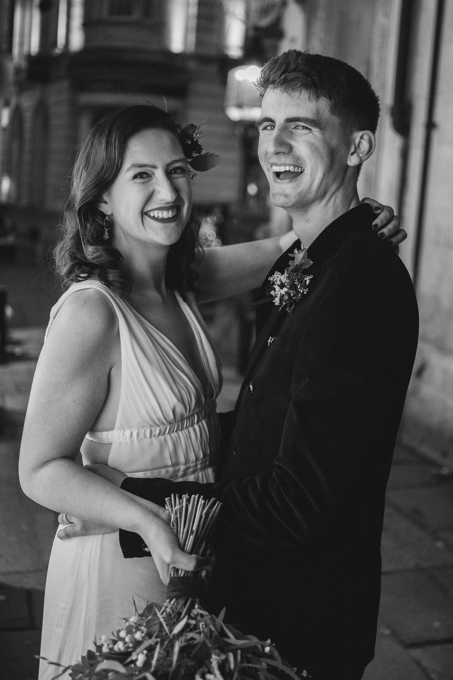 A couple shares a romantic black and white moment dancing together in formal attire.
