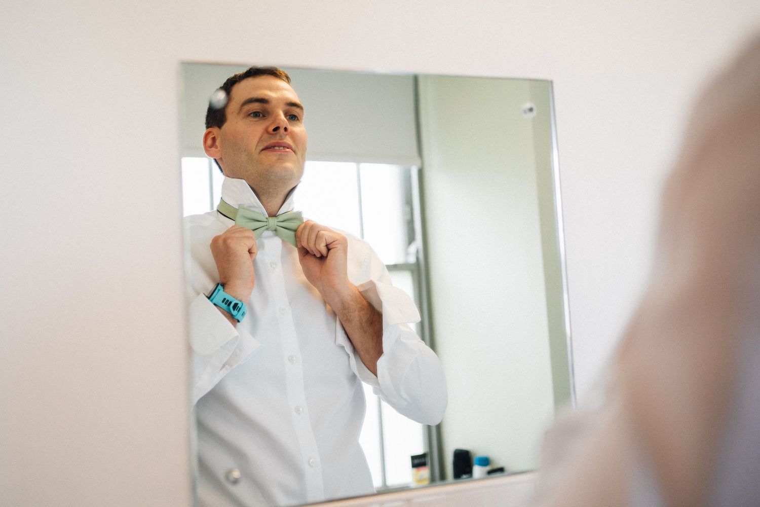 Someone adjusts a tie while getting ready in front of a mirror.