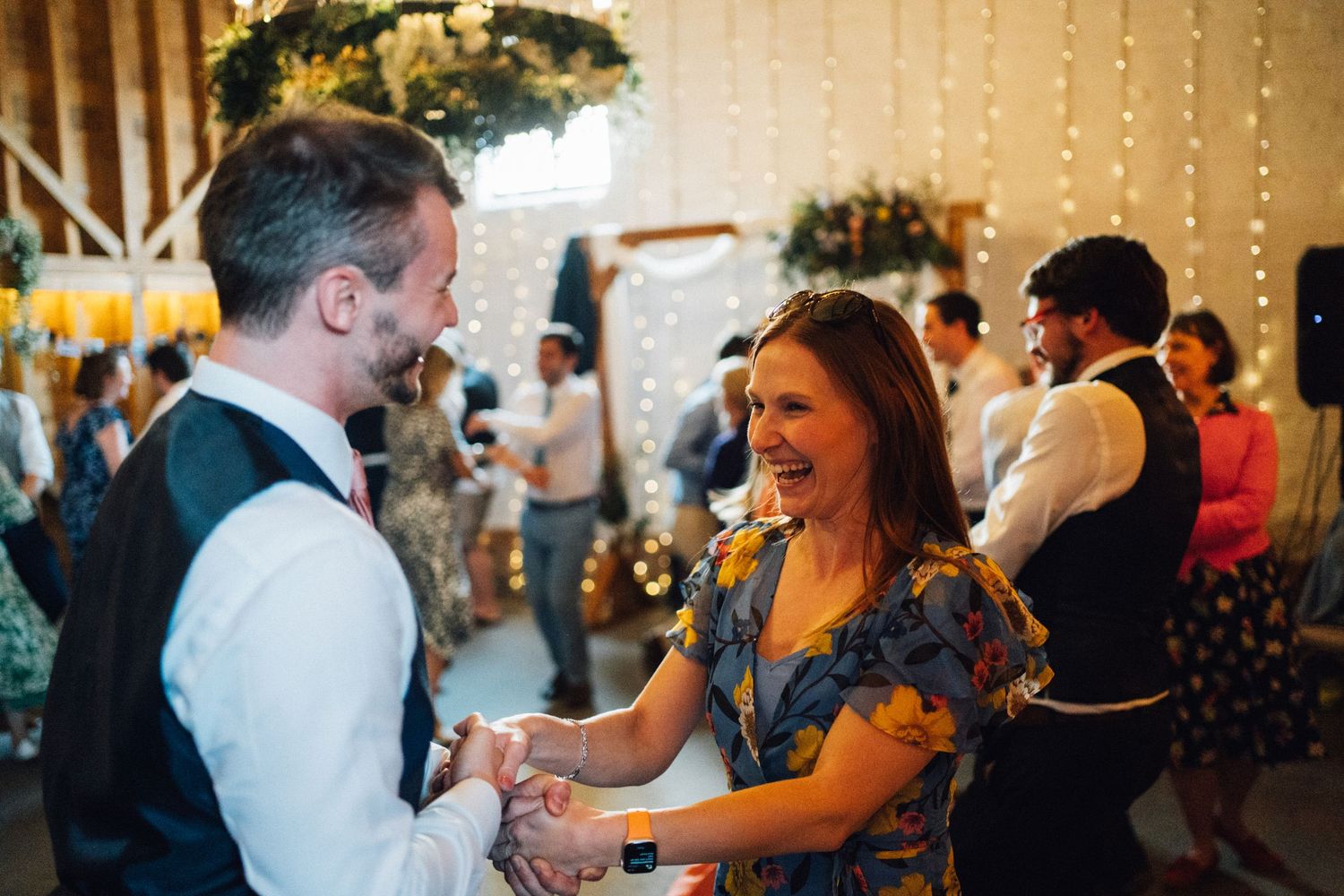 Wedding reception party in full swing with guests dancing under string light decorations.