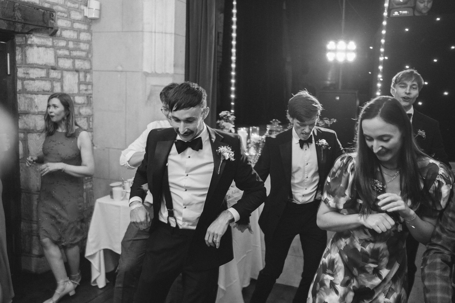 Black and white photo of wedding guests dancing and celebrating at reception.