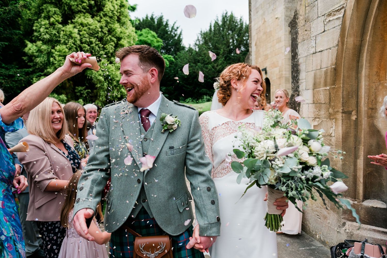 Guests celebrate with confetti outside a traditional stone church entrance.