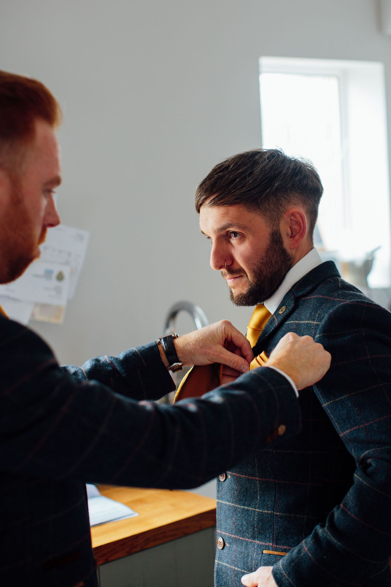 Two people in formal attire during a suit fitting session.