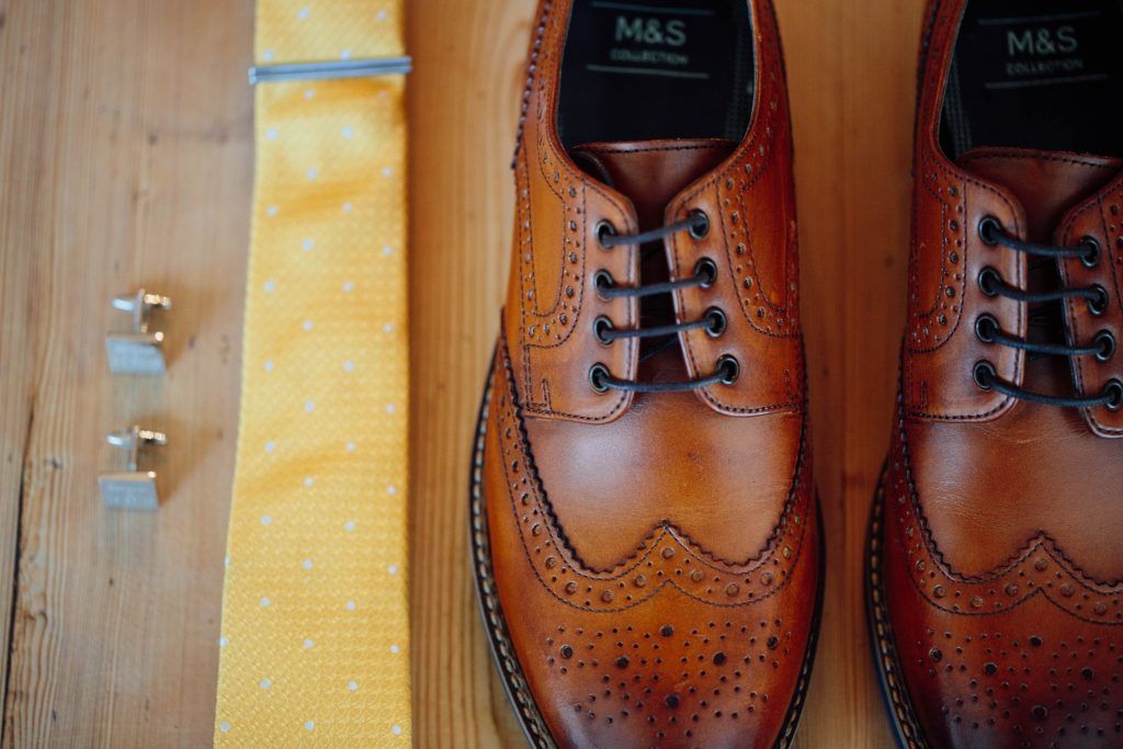 Close-up of brown leather dress shoes arranged in a row on wooden surface.