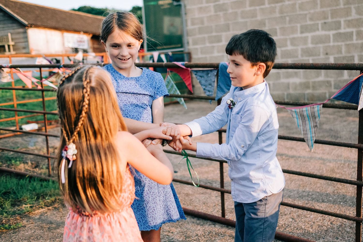 Children play together outdoors near wooden fence railings.