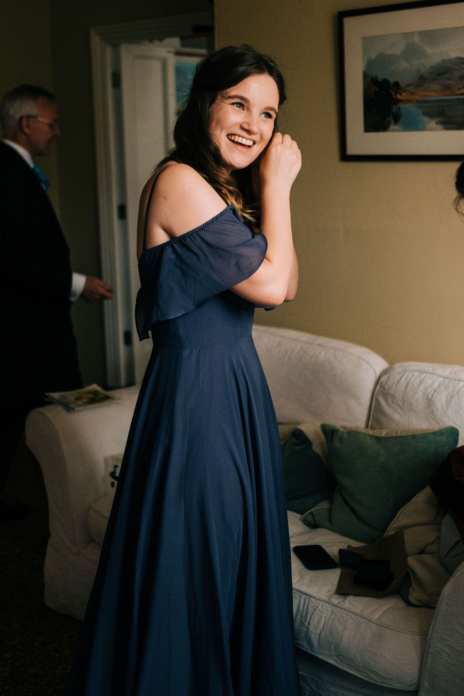 Woman in a navy blue dress twirling and posing in a living room setting.