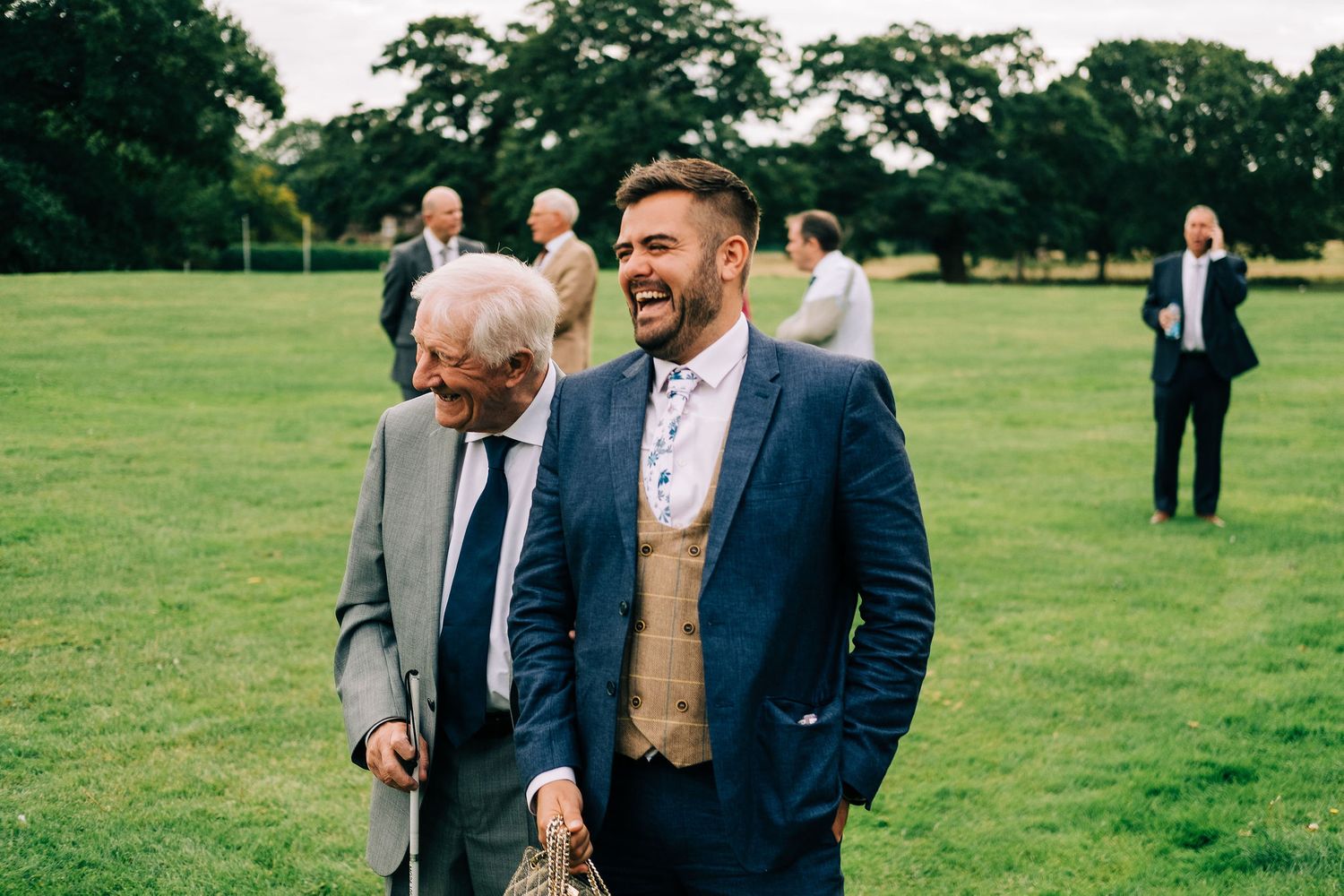 Wedding guests enjoying themselves on a sunny day in an outdoor garden setting.